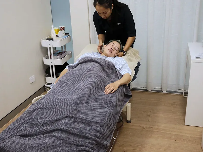 Practitioner applying a laser therapy handpiece to a patient’s neck